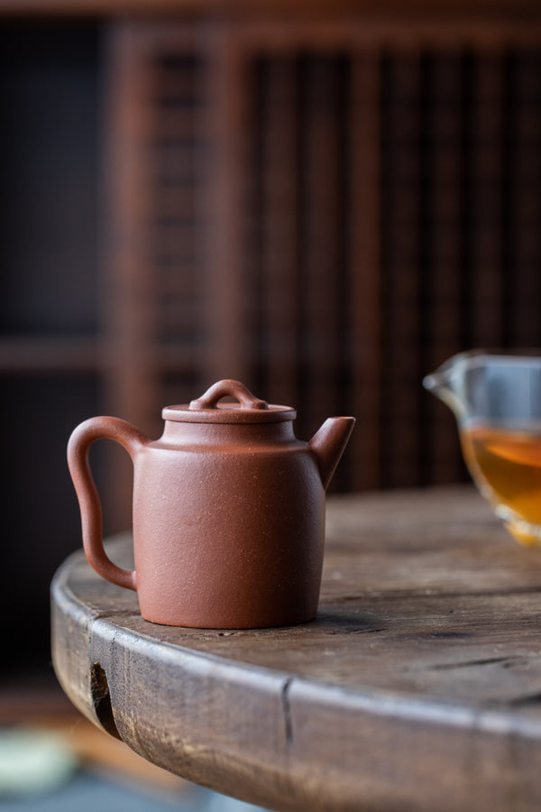 A dark clay teapot on a worn wooden table